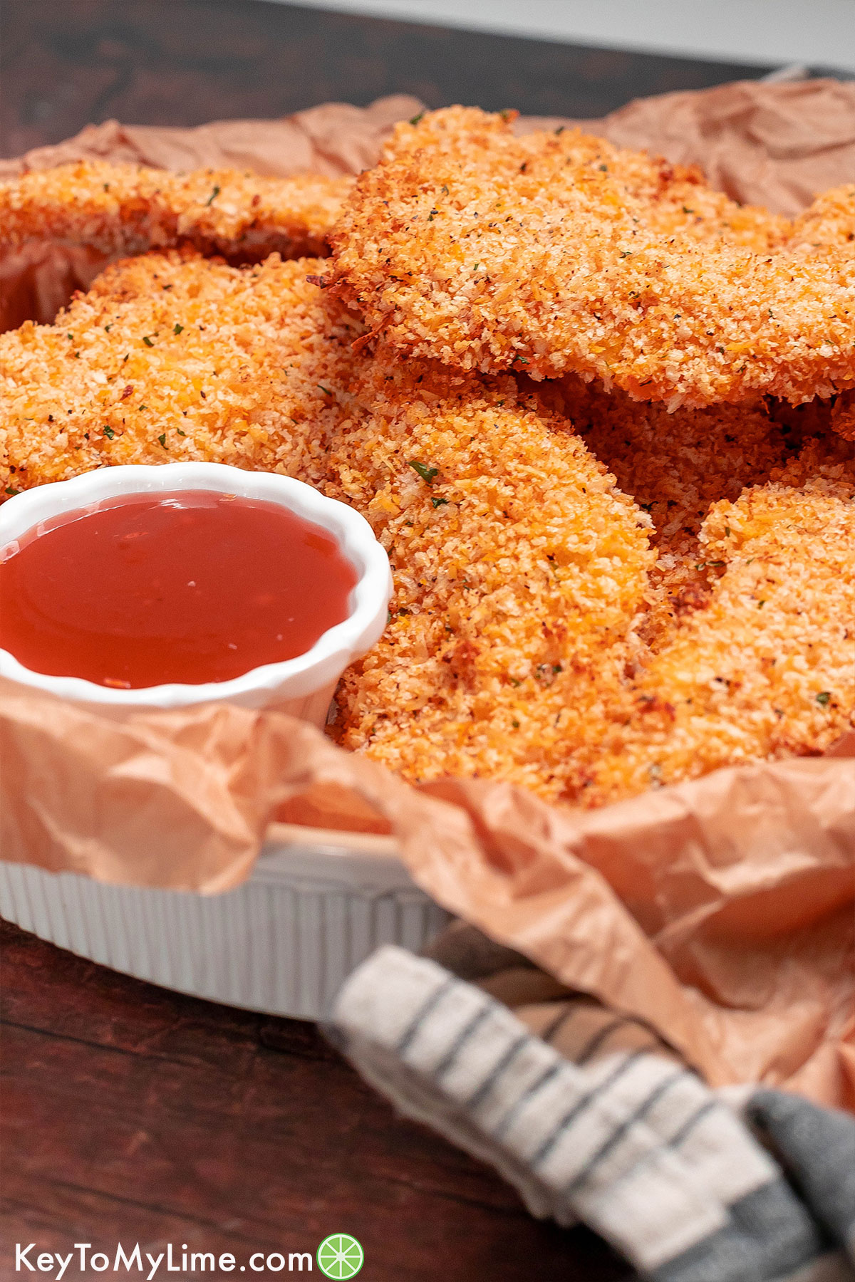 A side image of a stack of chicken tenders on top of a wooden table.