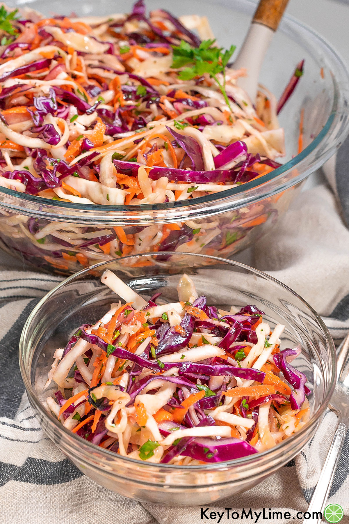 A side shot of two glass bowls filled with coleslaw.