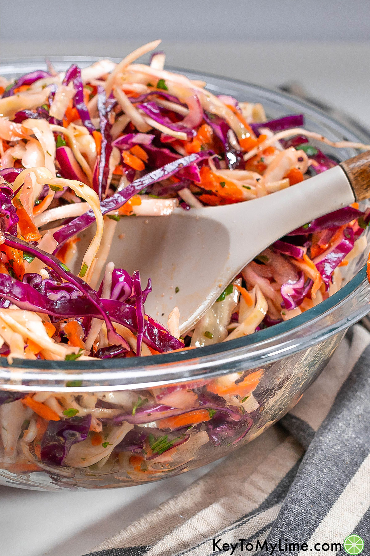 A close up image showing the texture of the mixed coleslaw on a serving spoon.