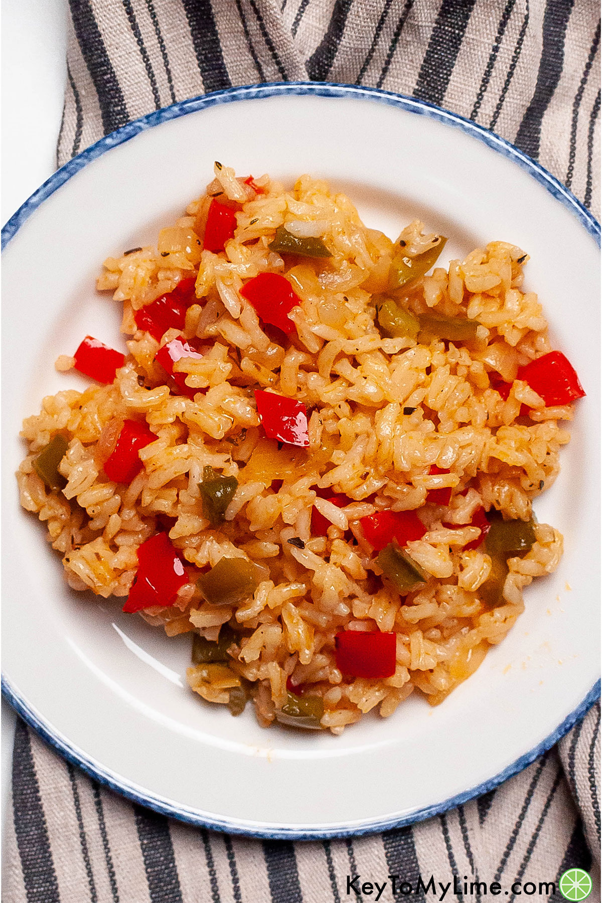 A serving of Cajun rice on a white plate with bell peppers throughout.