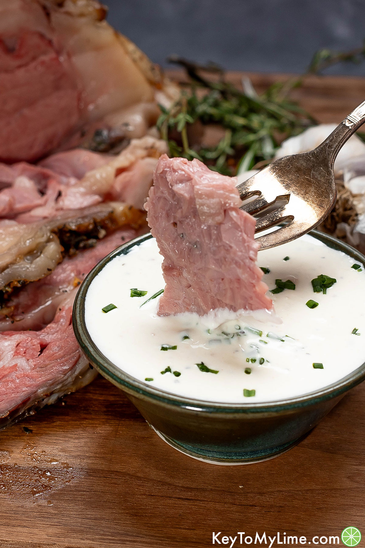 A forkful of prime rib being dipped in freshly made horseradish sauce.
