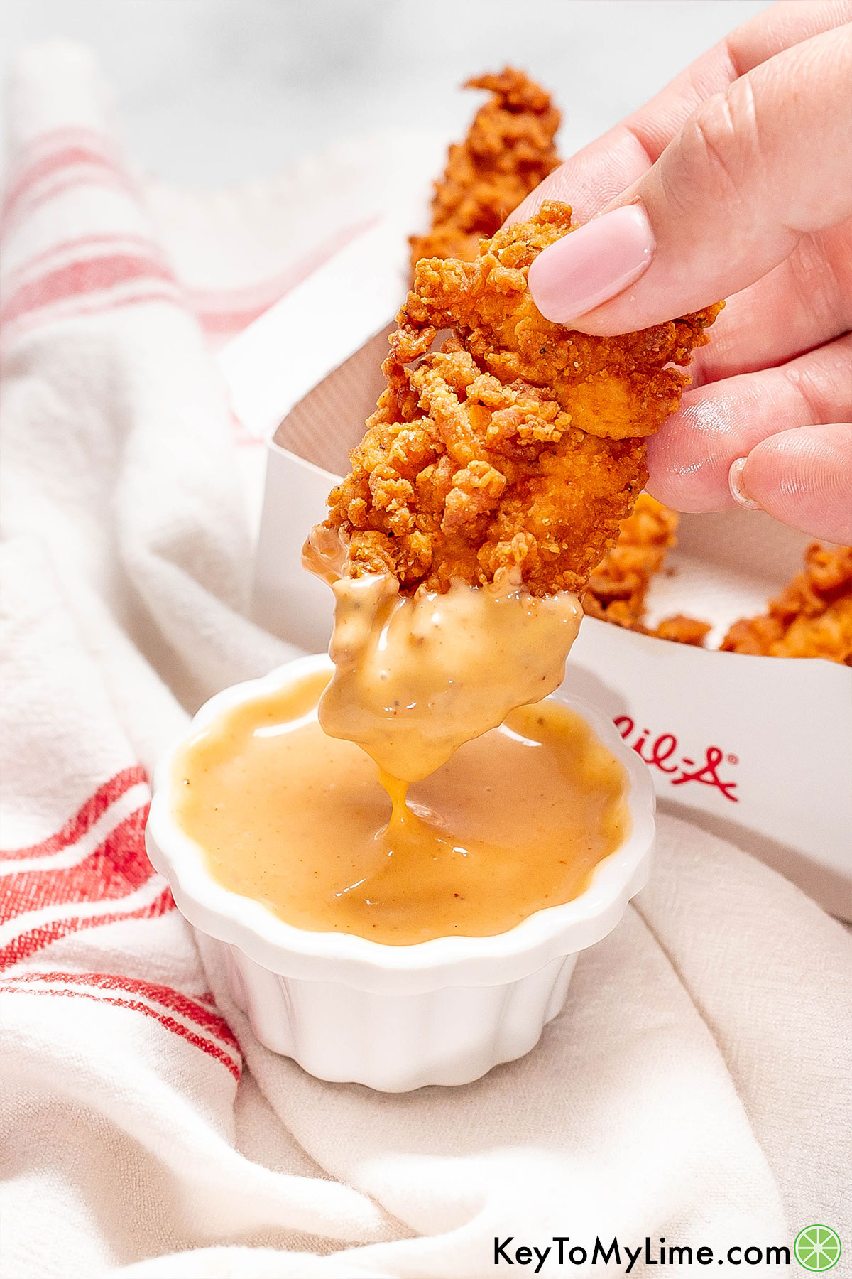 A crispy chicken tender with homemade Chick Fil A sauce on the lower half.