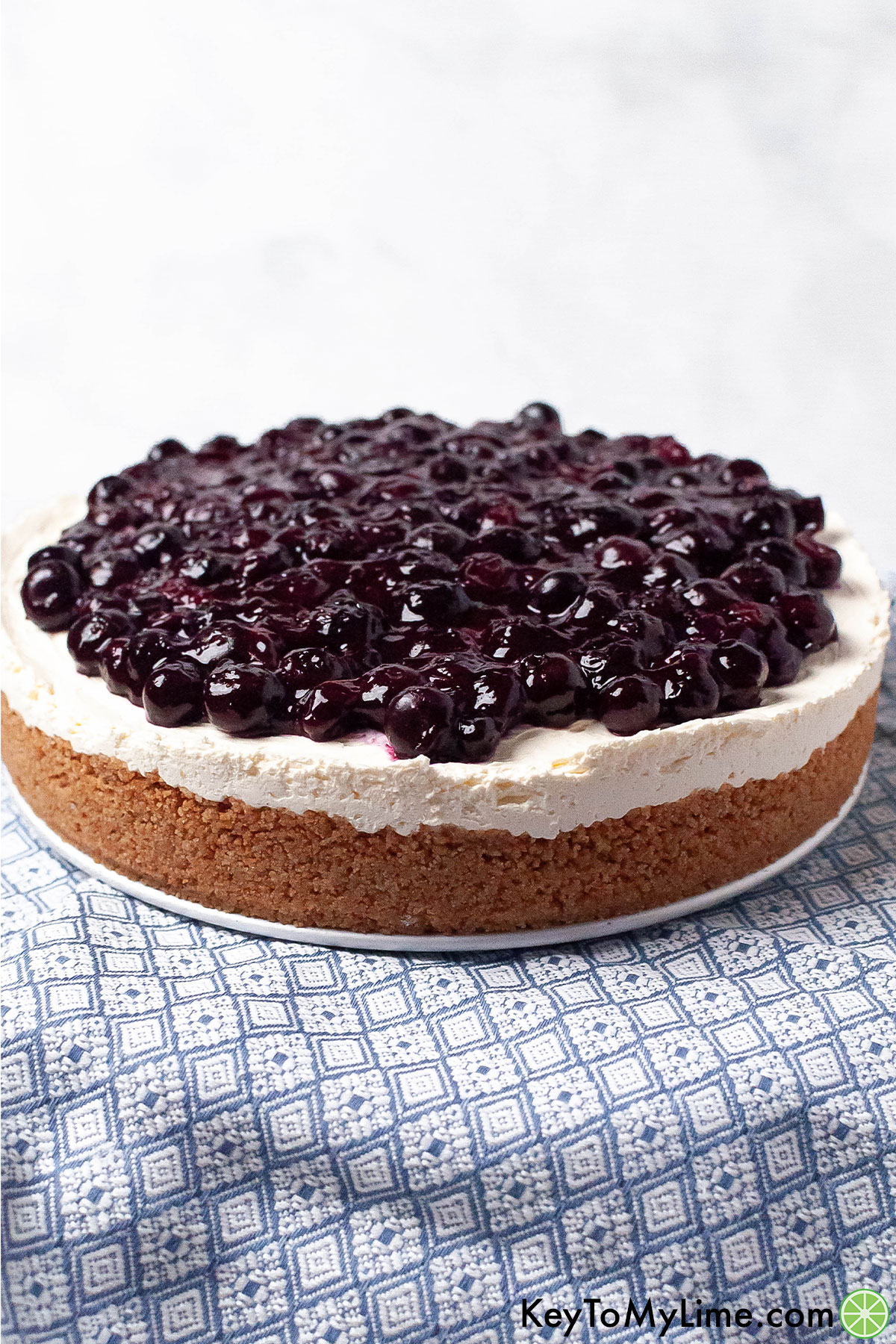 A completed blueberry cheesecake on a large platter on top of a blue napkin.