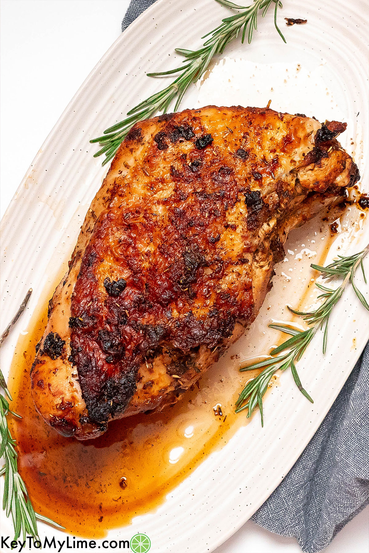 A juicy tender rested turkey breast garnished with rosemary.