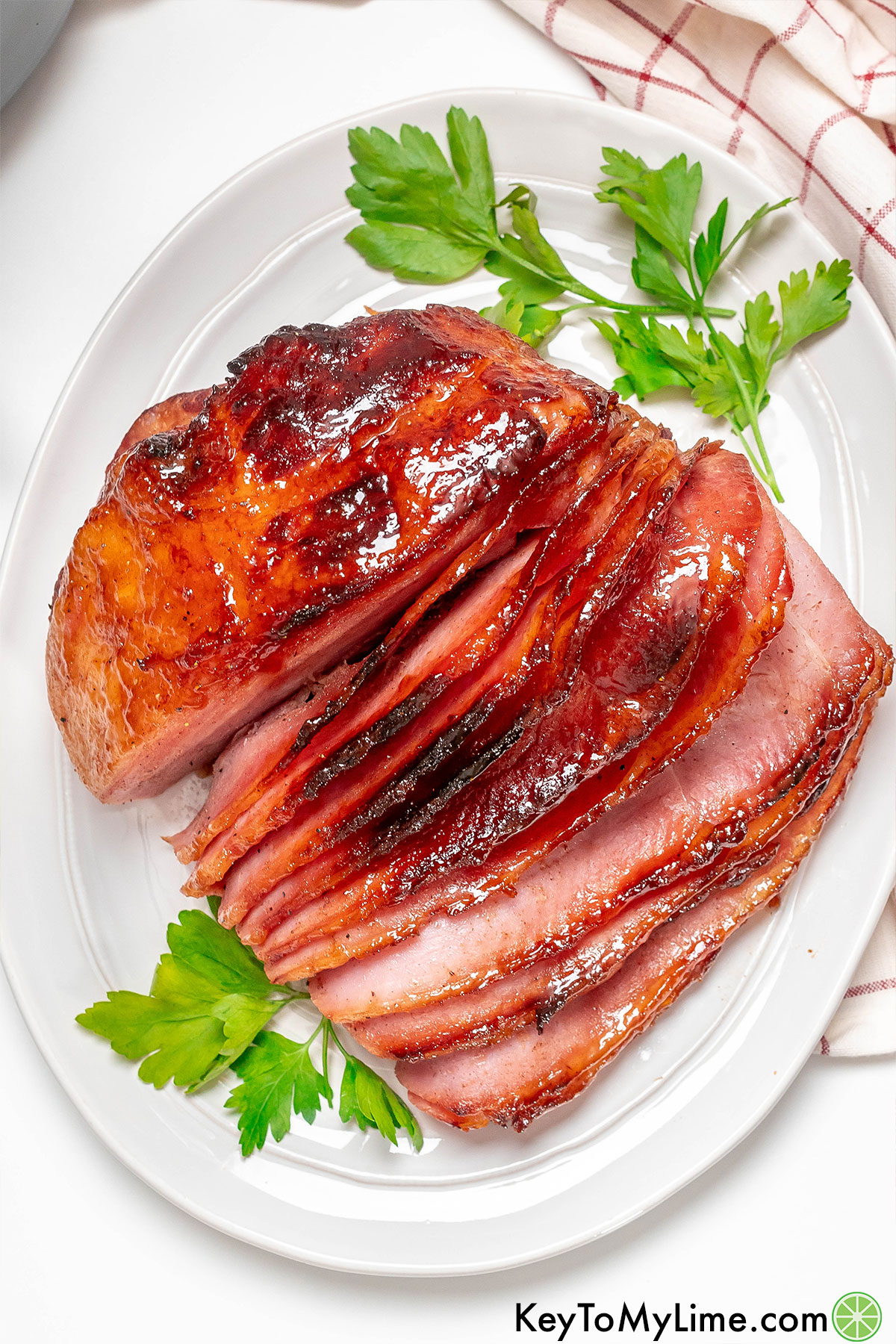 An overhead image of an air fryer spiral ham garnished with parsley on a white dish.