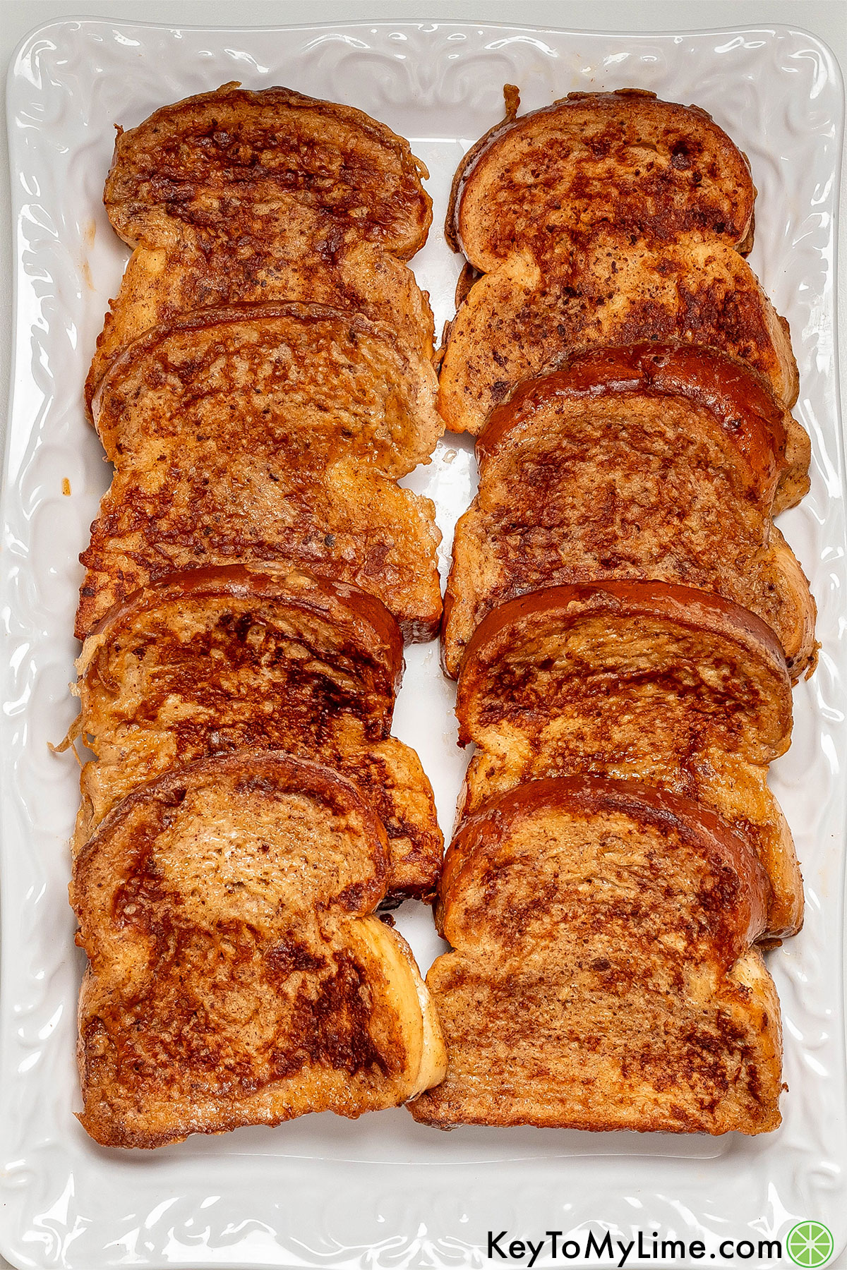An overhead image of perfectly cooked French toast showing the crispy golden texture on a large white platter.