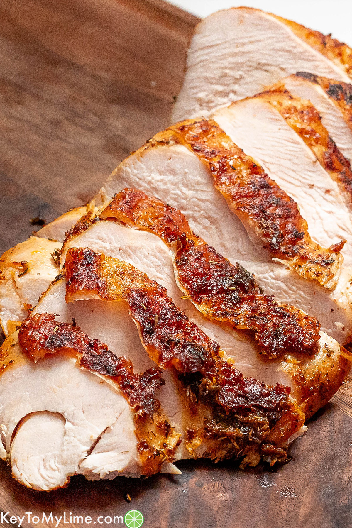 A side image of a turkey breast cut up into thick slices with golden crispy skin.