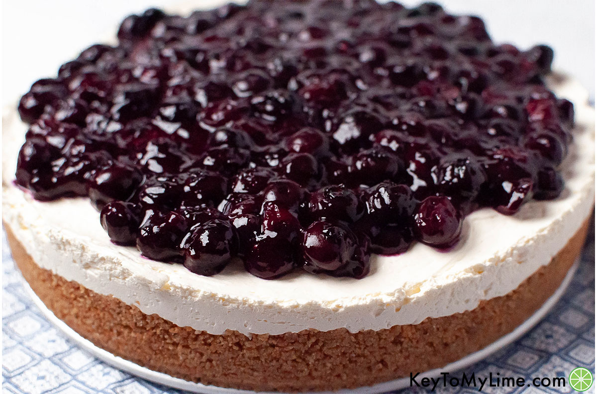A fully finished cheesecake with glistening blueberries on top.