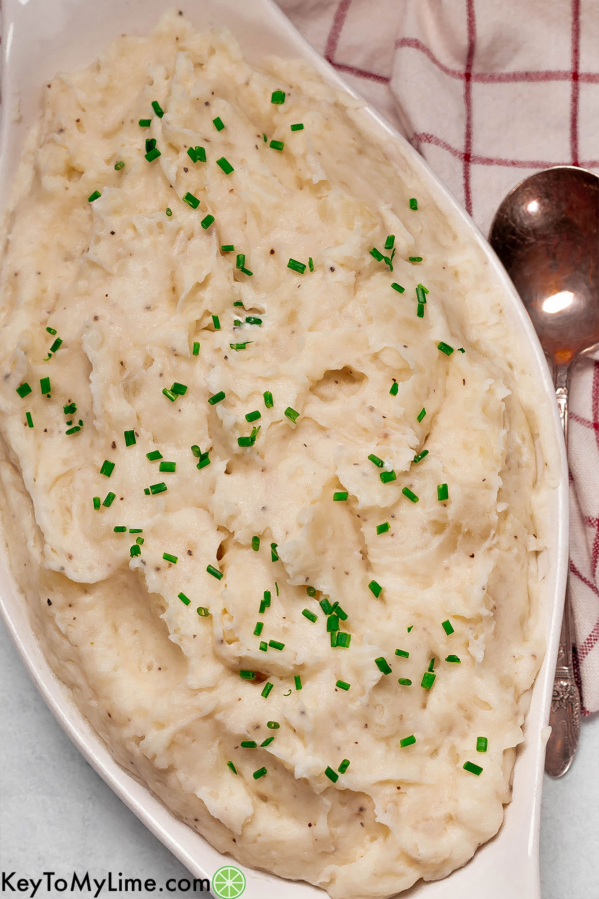 An overhead image of a large serving dish filled with mashed potatoes with swirls throughout.