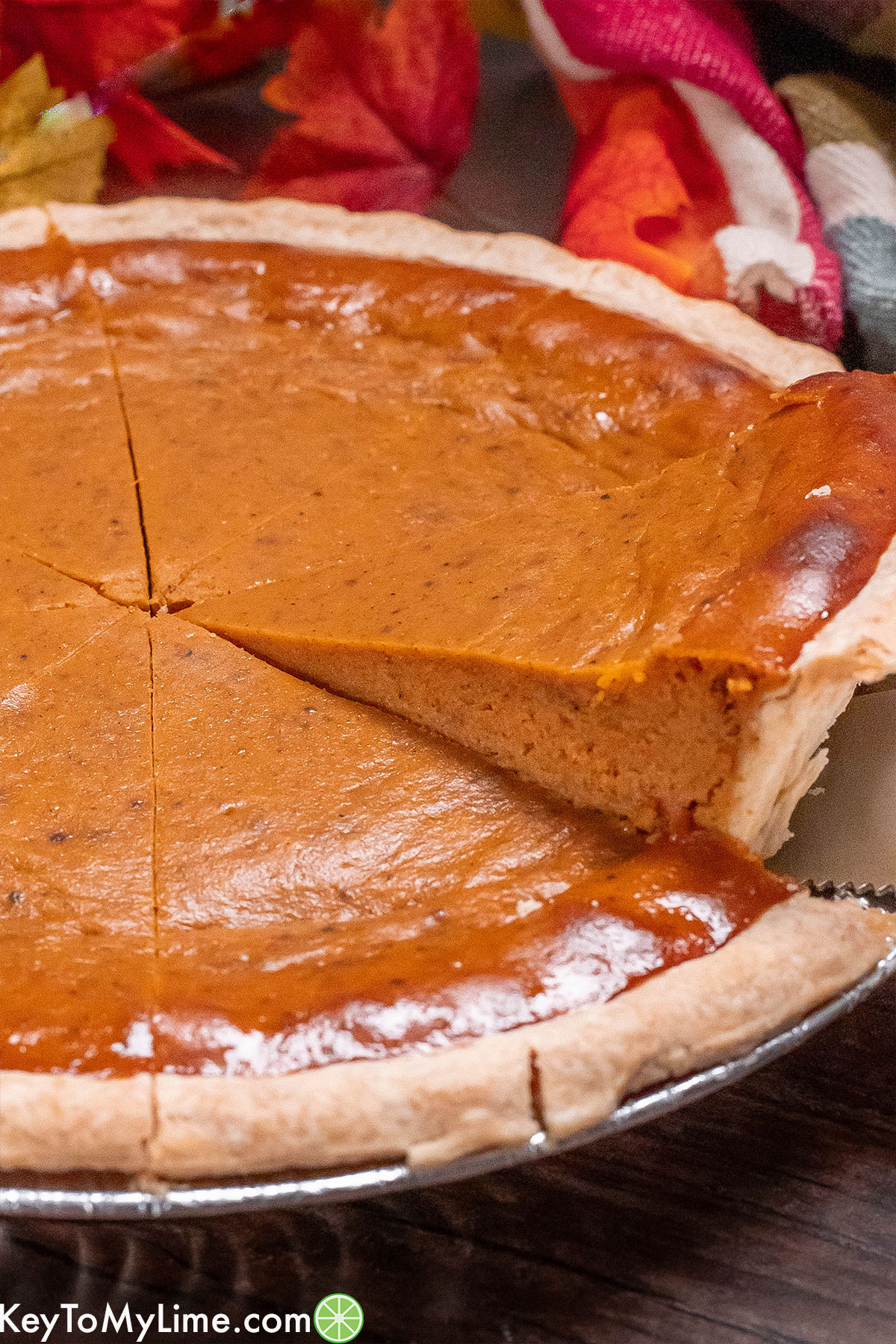 A slice of pumpkin pie being lifted out of a pie dish.