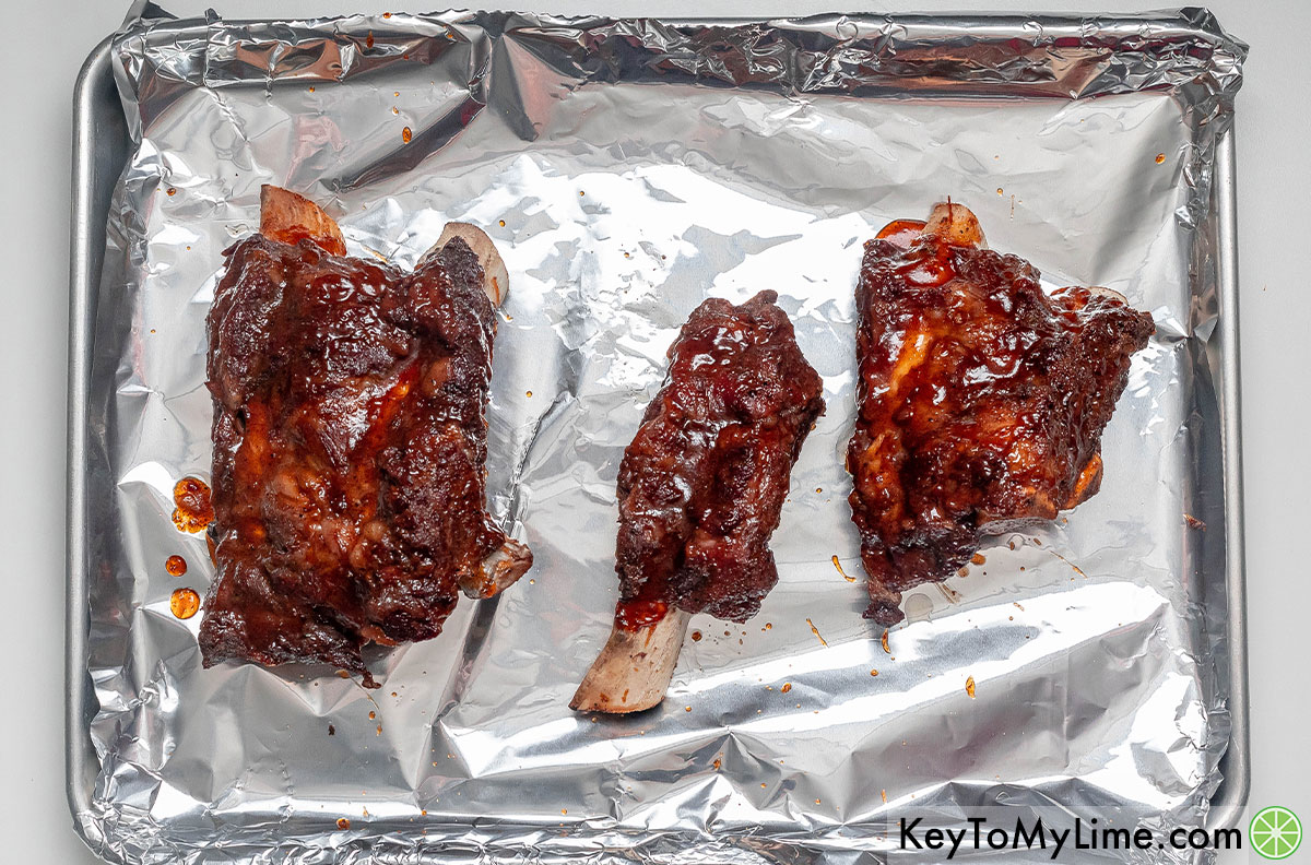 Placing the ribs back in the oven, and then broiling.