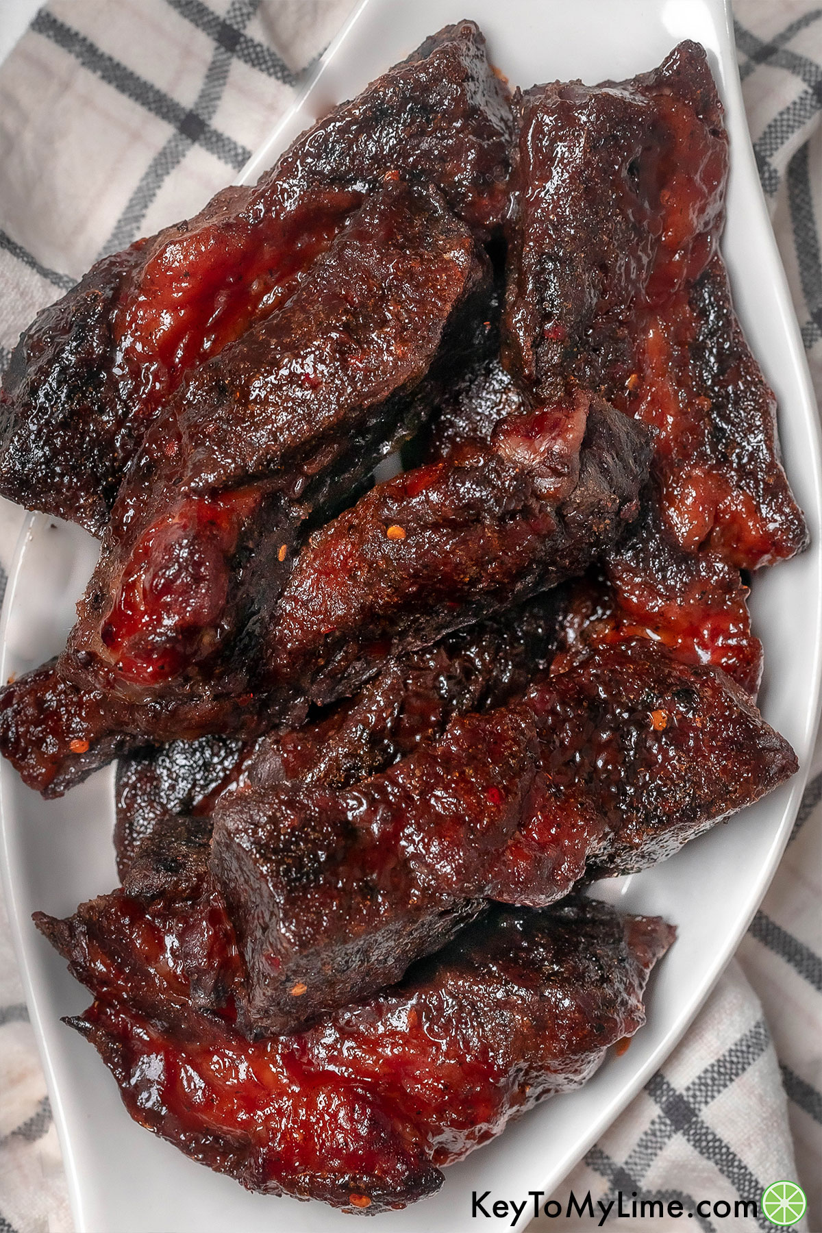 An overhead image of beef ribs on a plate over a napkin.