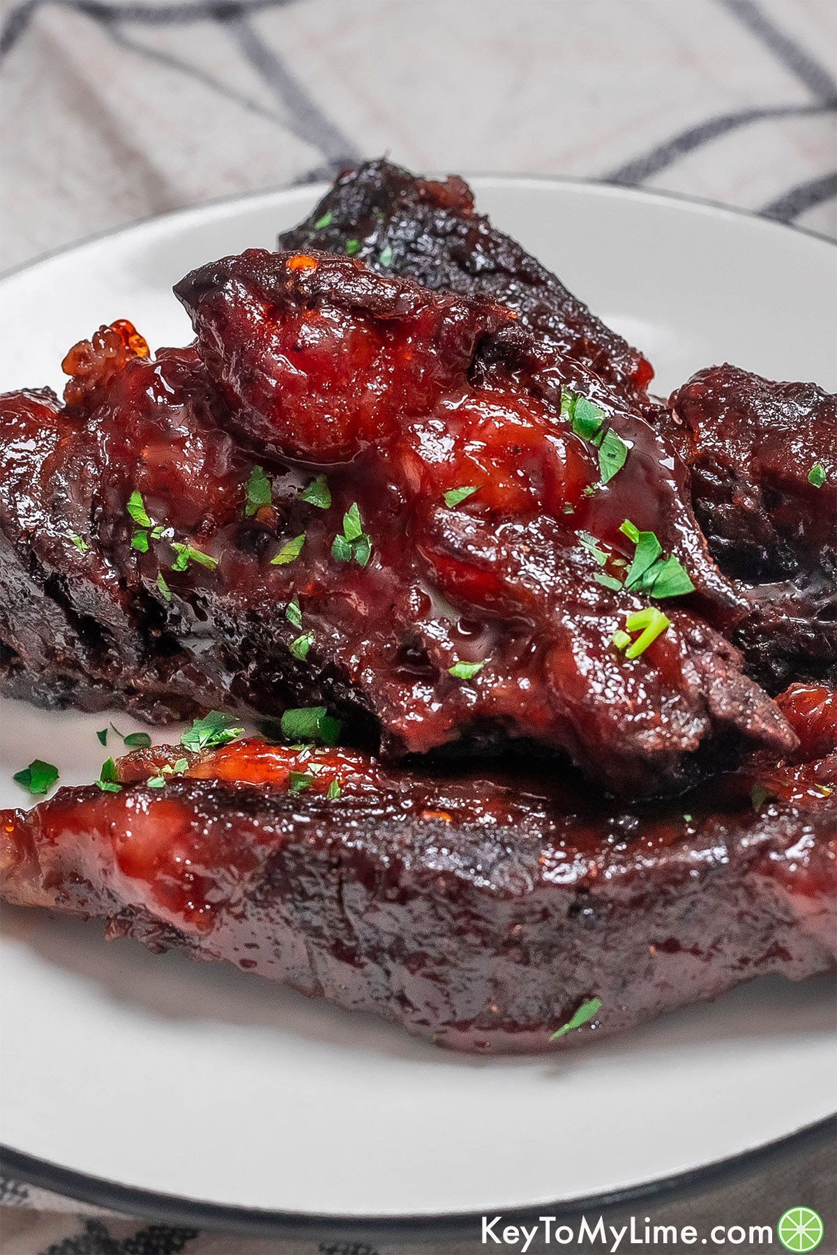 A side image of tender beef ribs garnished with fresh parsley.