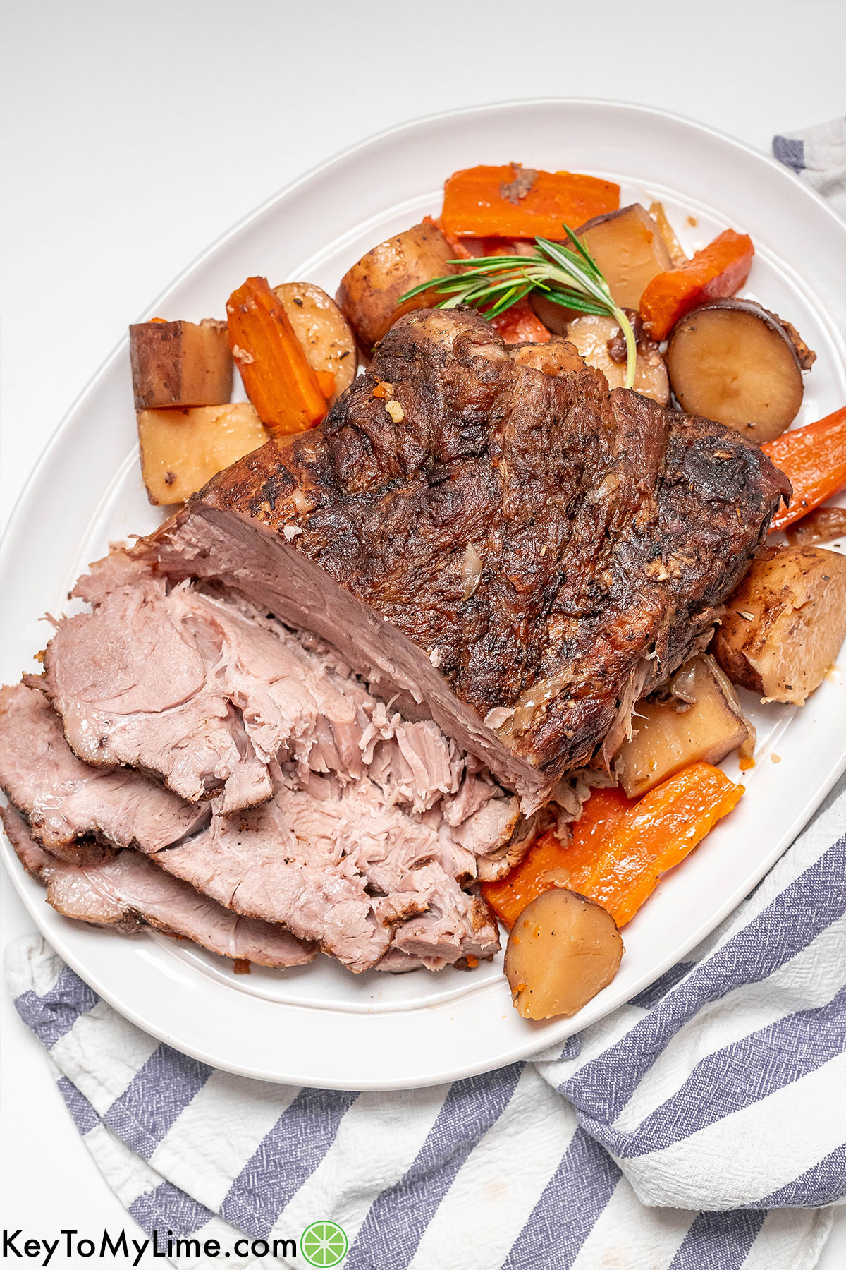 An overhead image of a shredded pork roast on a platter with carrots and potatoes.