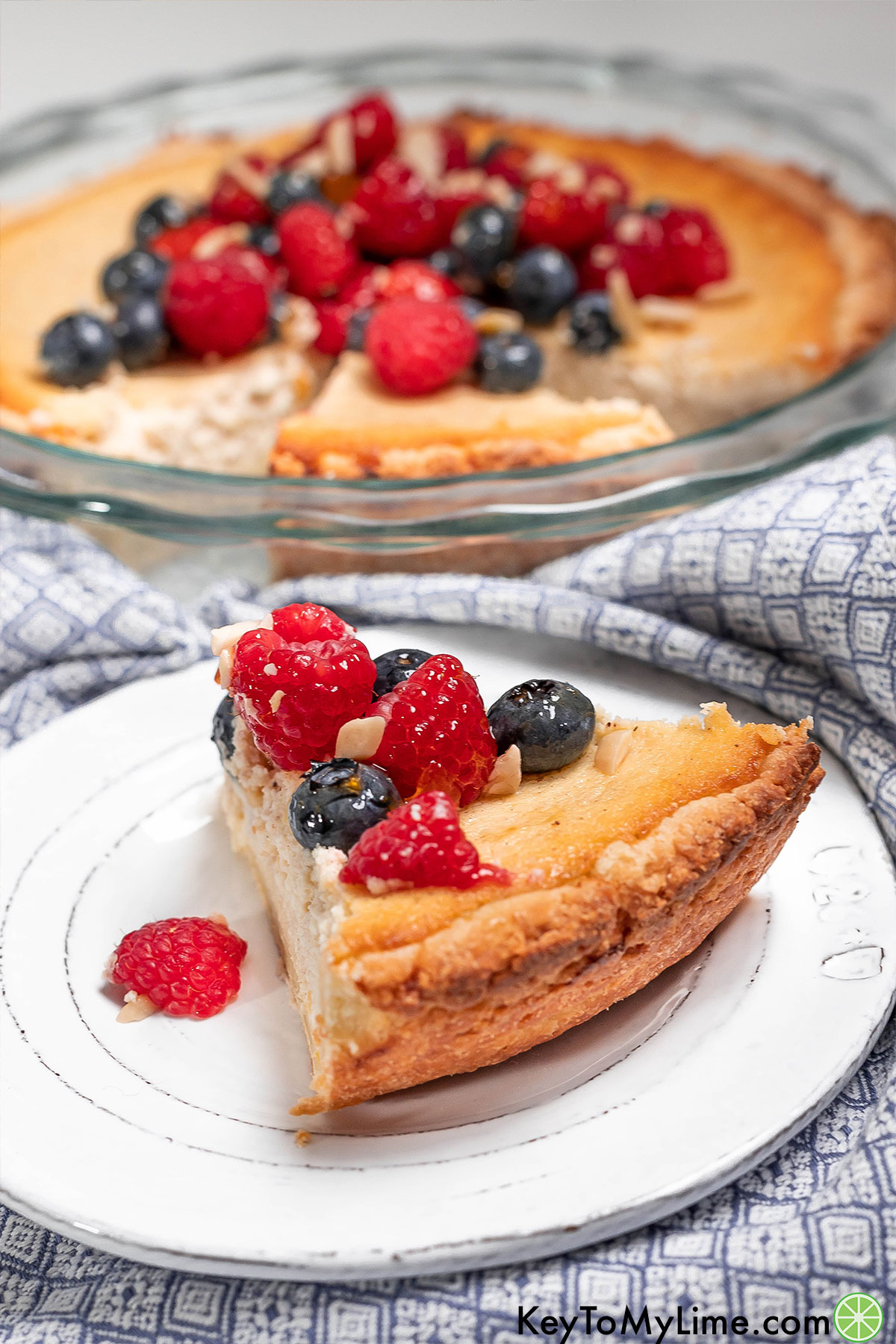A slice of golden brown buttery crust pie garnished with fresh berries on top.