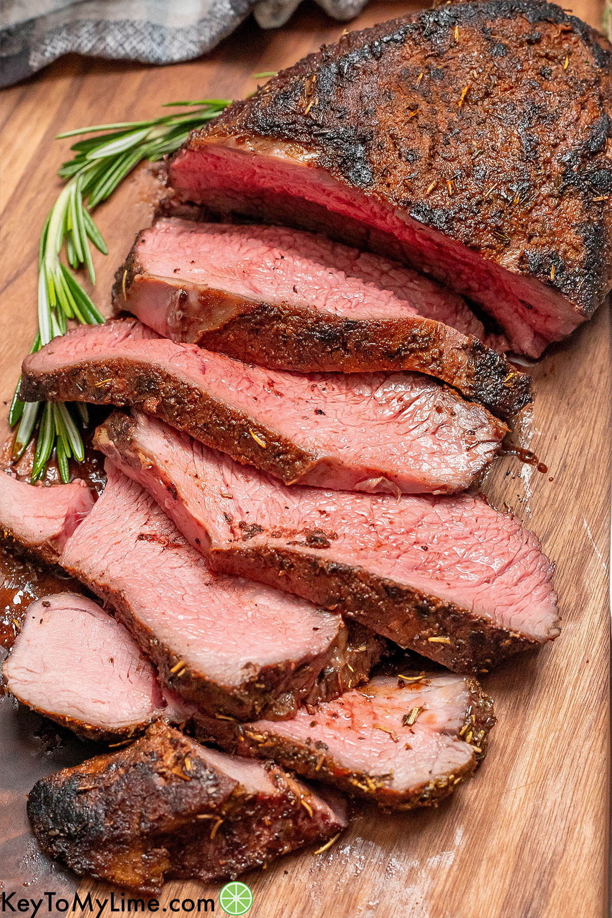 Tri tip slices staggered on a cutting board showing the seasoned bark on top.