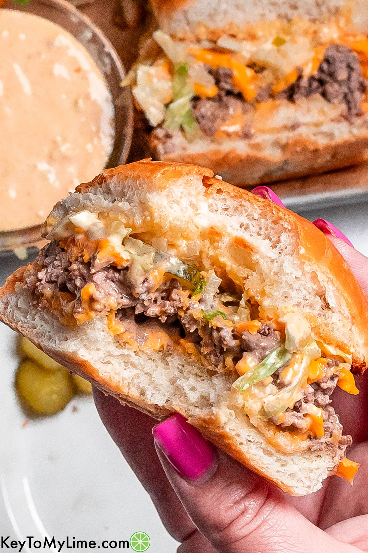 A close up image of a partially eaten big mac slider showing the cheesy layers inside.