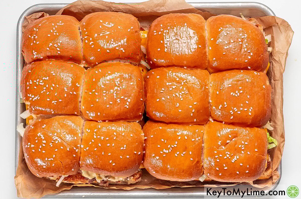 Lightly brushing the tops of the slider buns, and then topping with sesame seeds.
