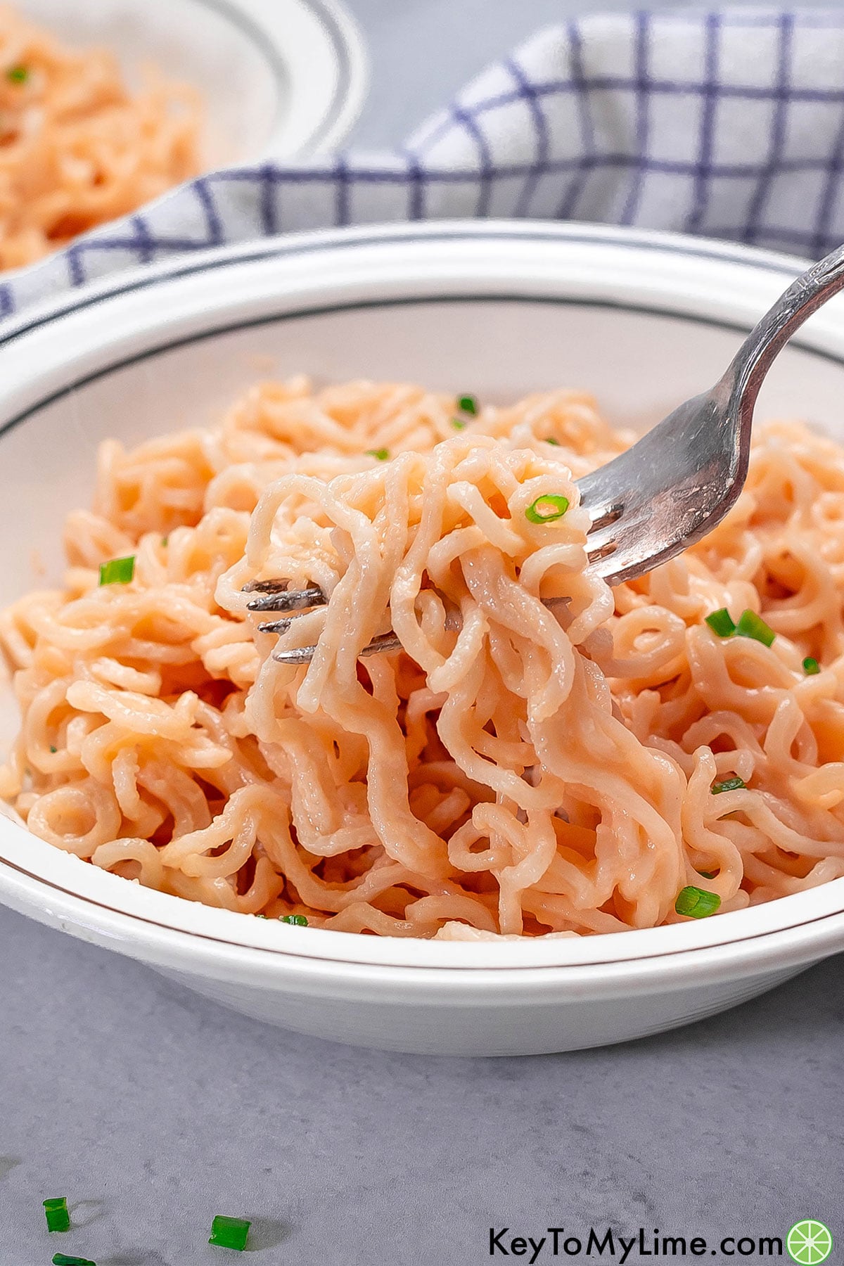 A close up image of a cheesy ramen dish served in a small white bowl.
