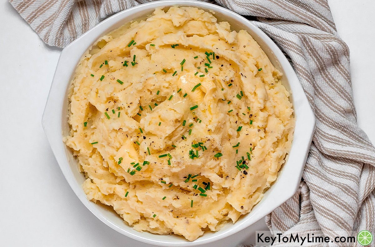 Mixing the rest of the milk and butter into the potato mixture, and then transferring to a serving dish to garnish with fresh chives.