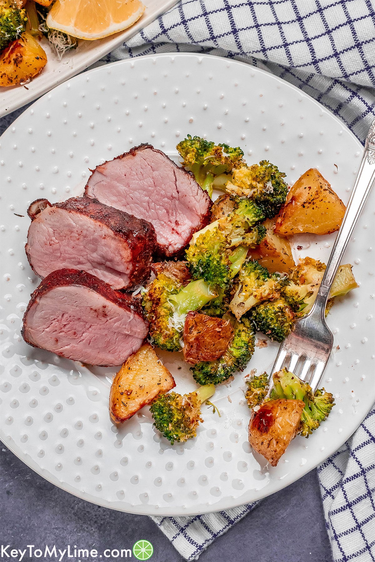 A tenderloin dinner with a side of roasted vegetables with napkin underneath.