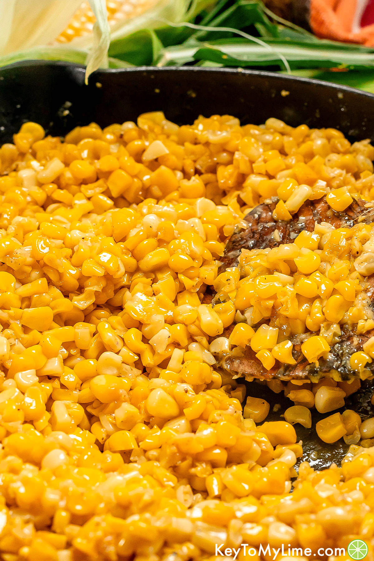 A close up image of a cooked corn being lifted out of a skillet.