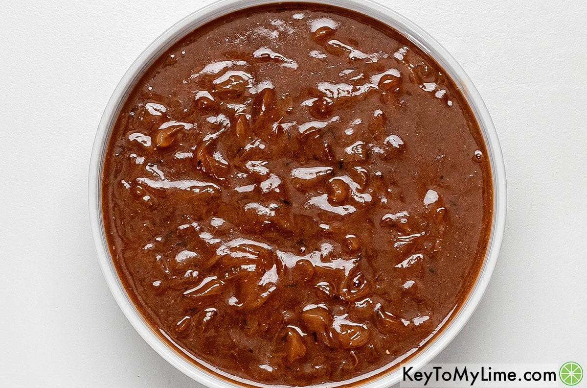 Transferring the onion gravy to a serving dish.