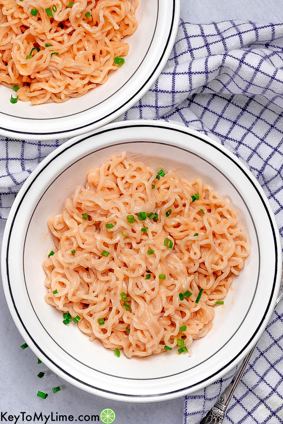 An overhead image of two bowls filled with ramen with a blue napkin underneath.