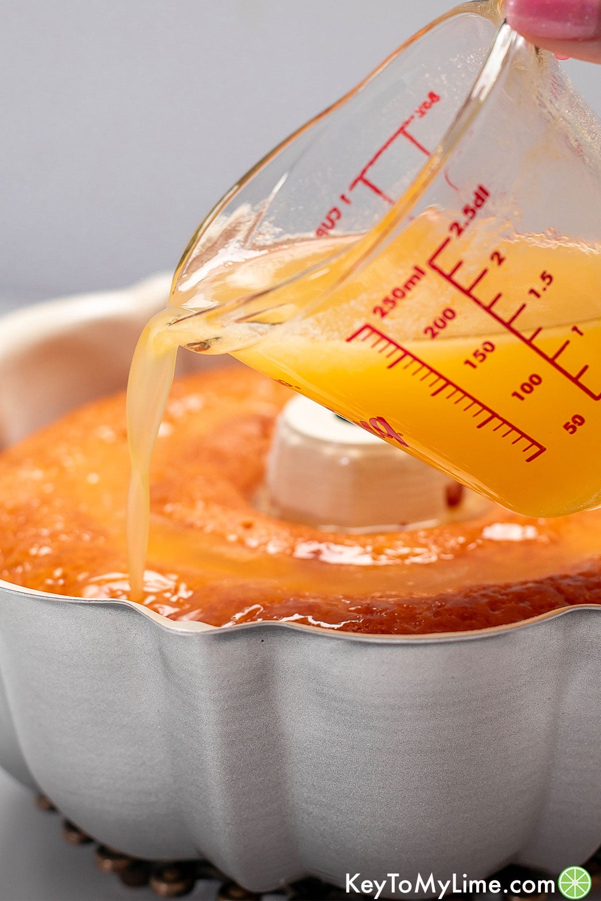 A side image showing the warm orange juice syrup being poured over the freshly baked cake.