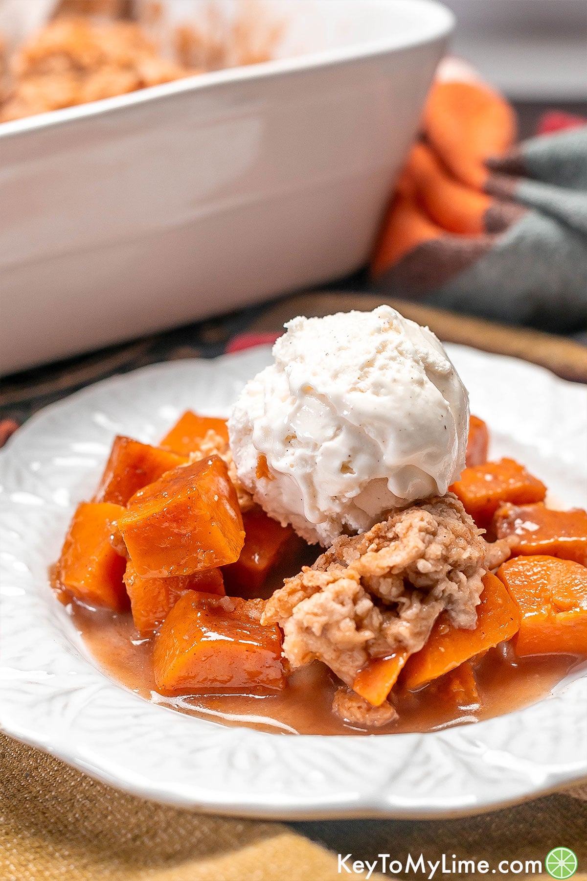 A close up of a serving of sweet potato cobbler with a dollop of ice cream on top.