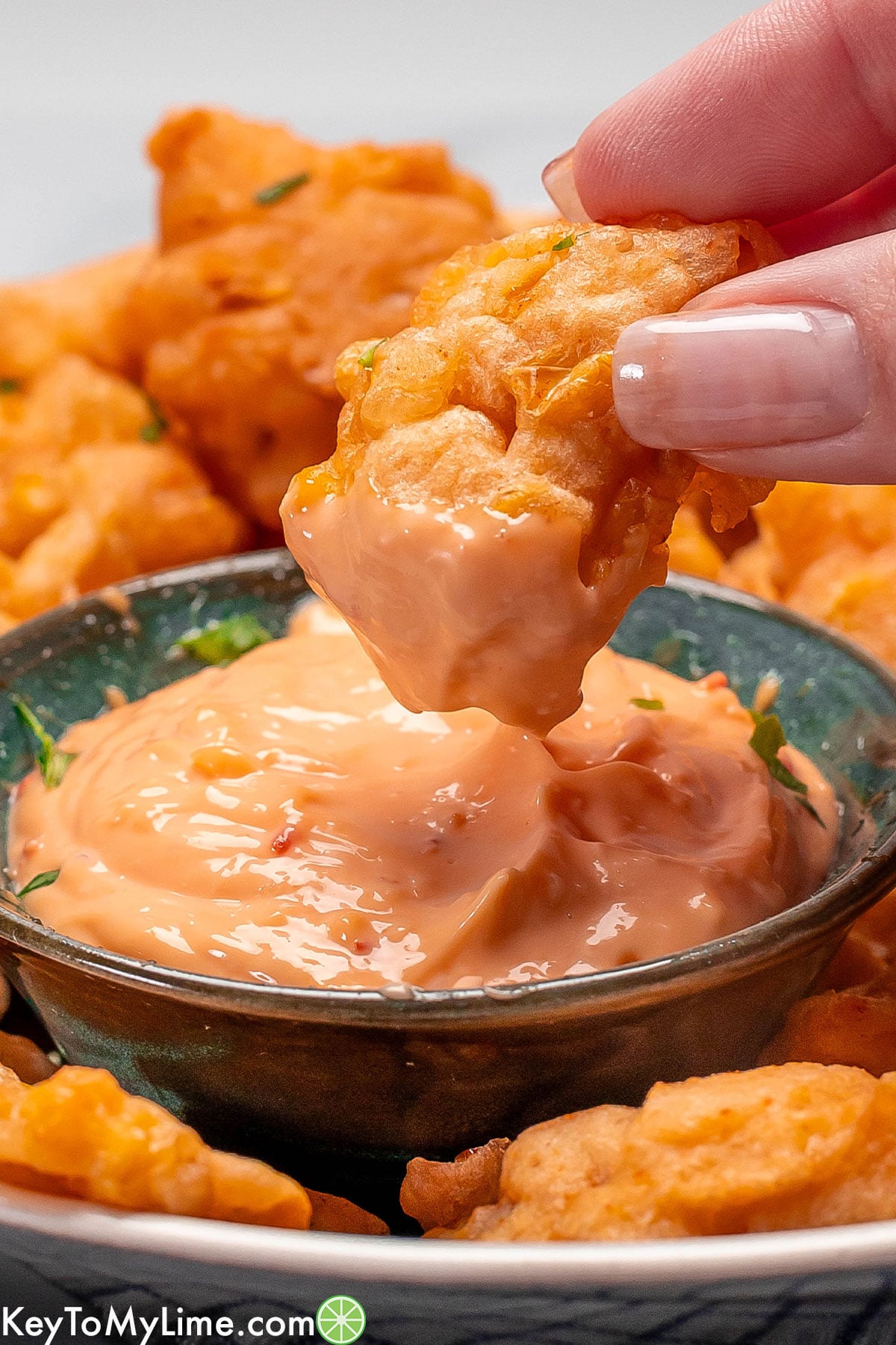 A side image of a corn nugget dipped in dipping sauce.