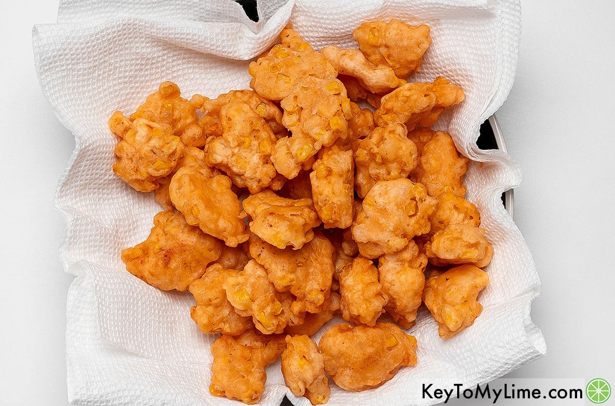 Transferring the corn nuggets to a paper towel after cooking to absorb excess oil.