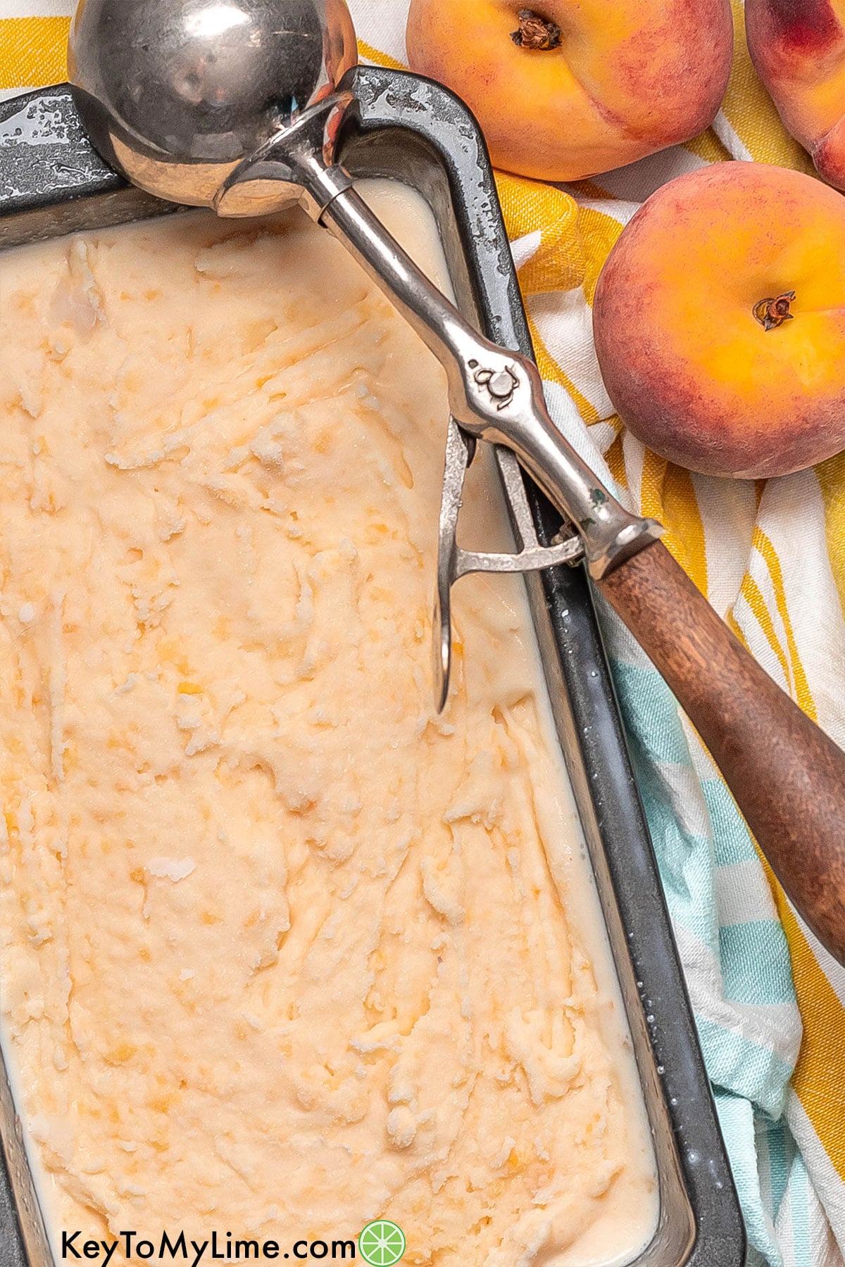 Freshly whipped ice cream resting in pan with ice cream scoop to the side.