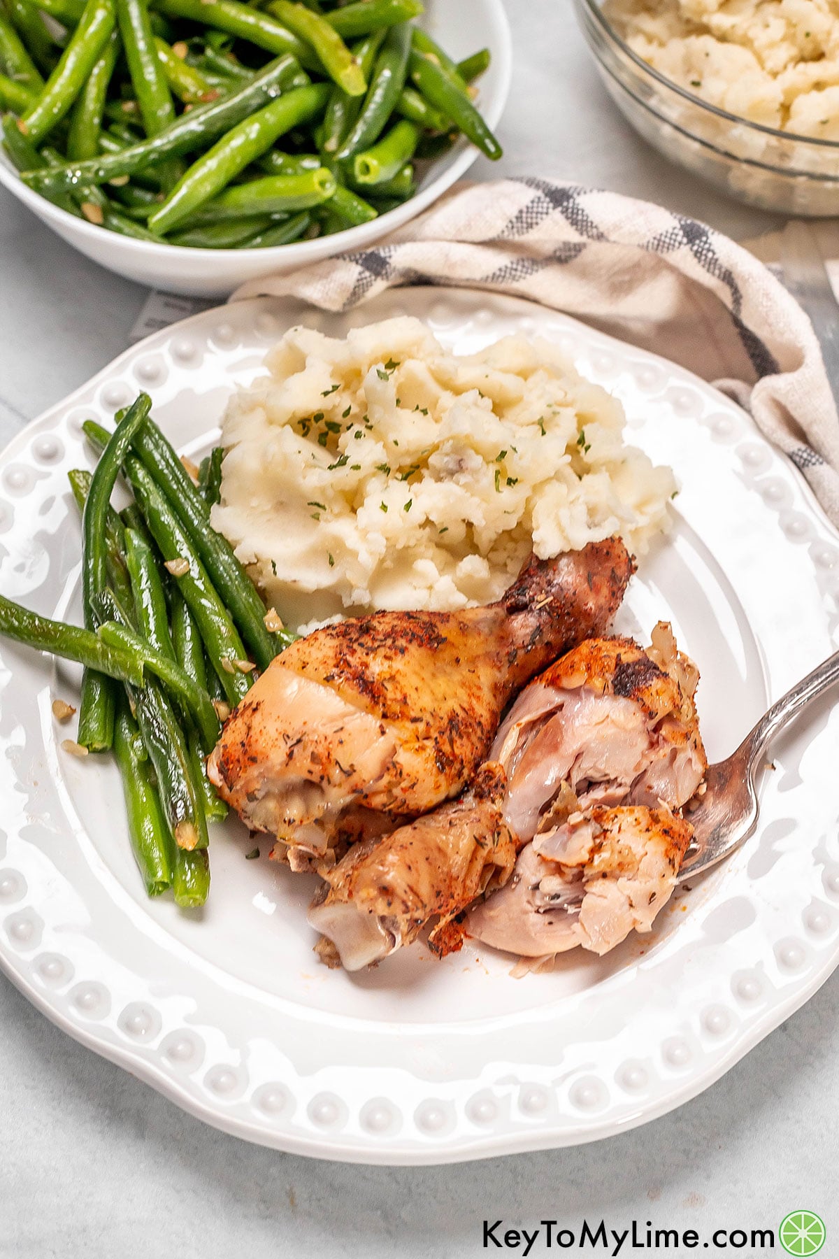 A serving plate filled mashed potatoes and a couple of chicken drumsticks.