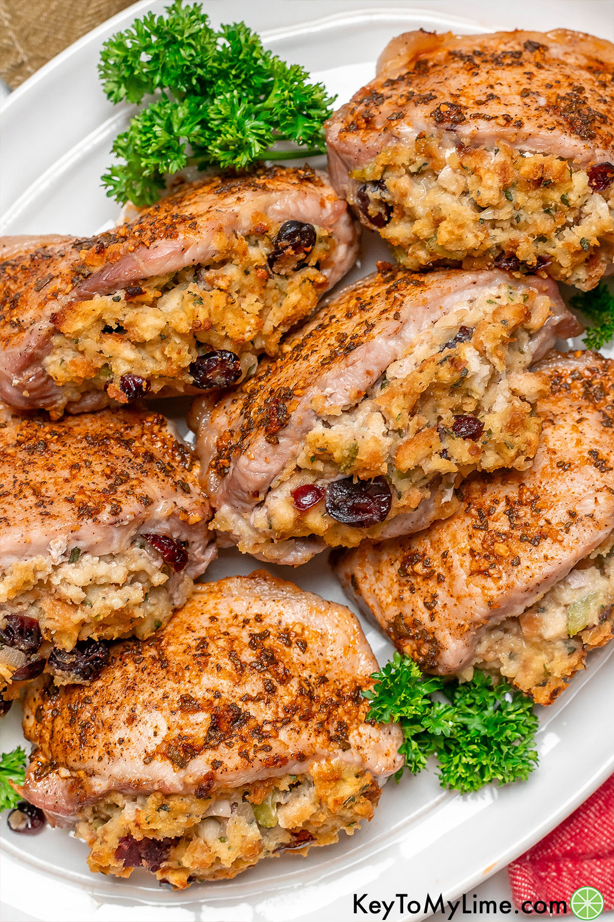 A stack of pork chops with garnish to the side resting on a large white platter.