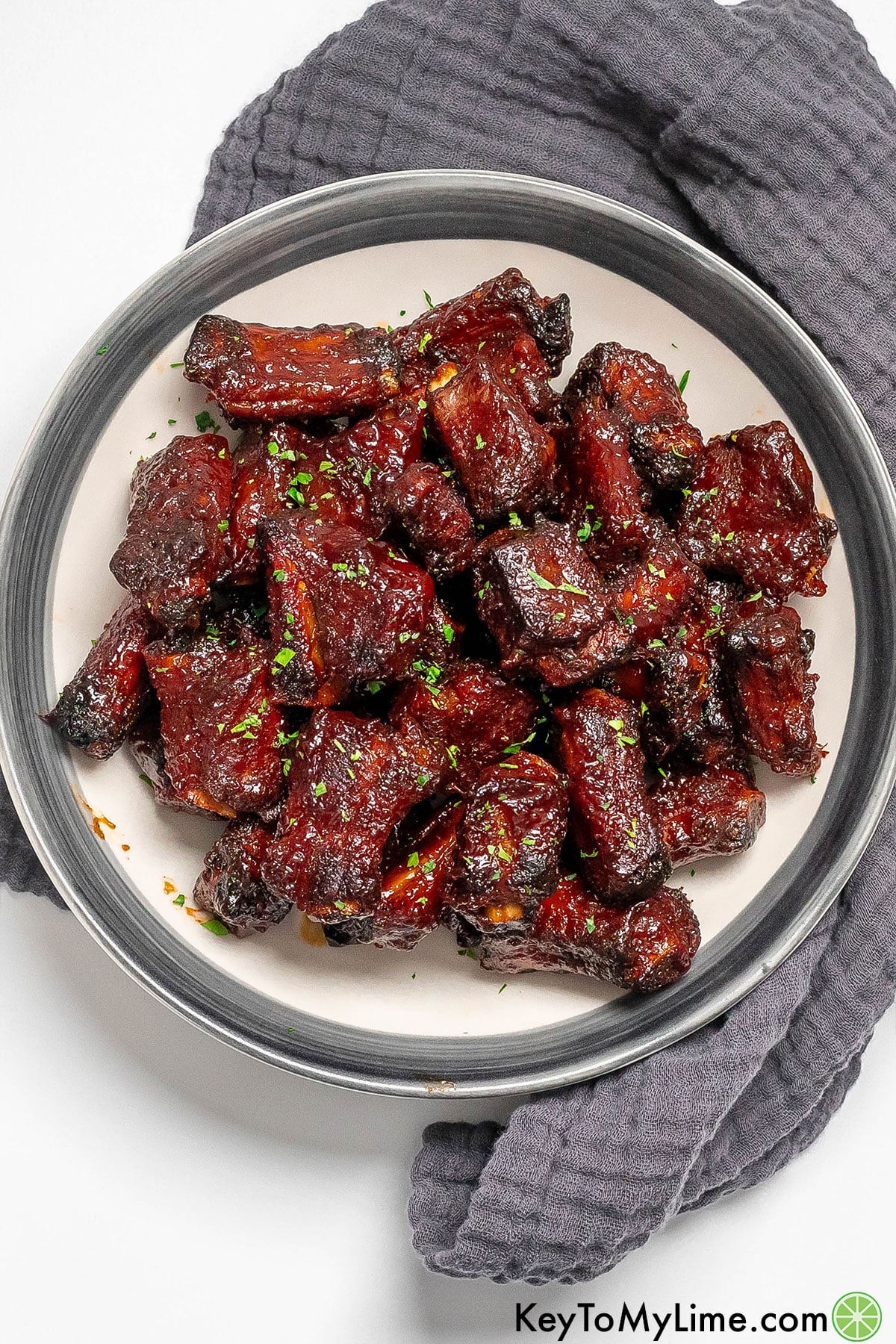 An overhead image of riblets on a large plate with a napkin underneath.