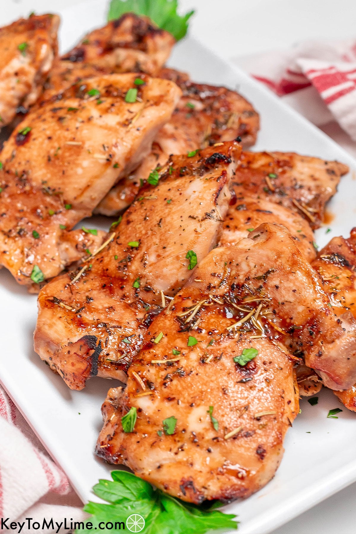 Chicken thighs stacked on top of each other on a large white platter.
