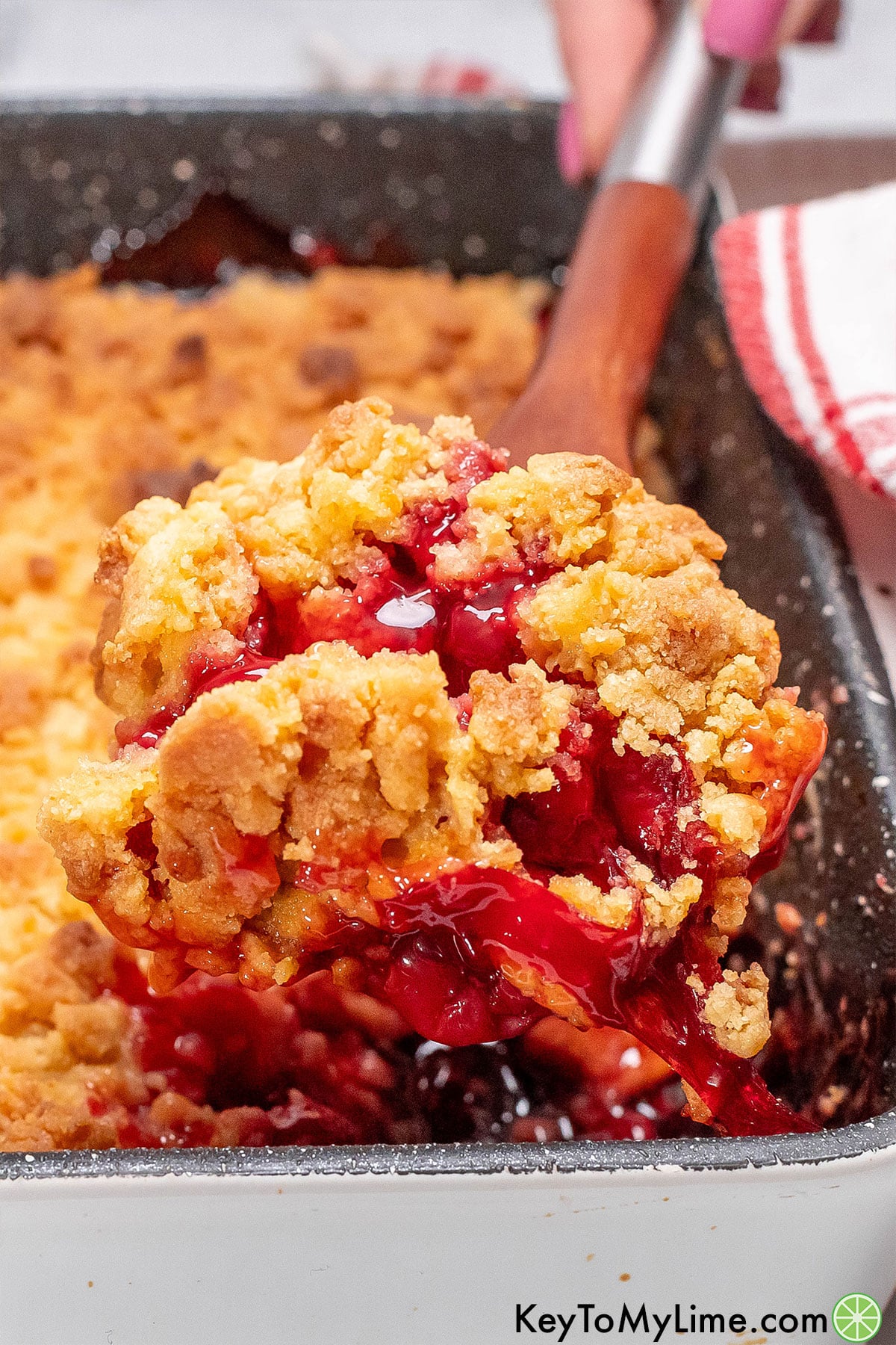 A close up image of cherry cobbler on a serving spoon.