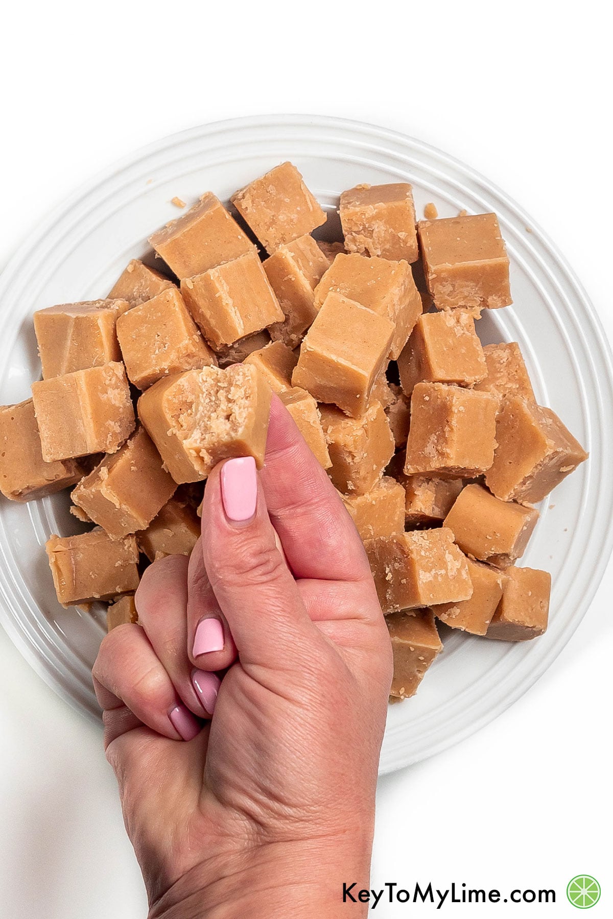 Holding a peanut butter fudge with a bite missing.