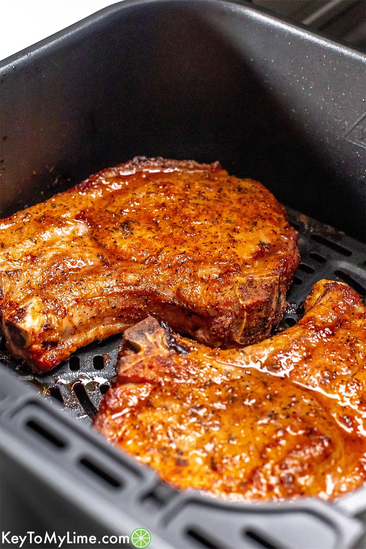 Juicy pork chops in an air fryer basket.