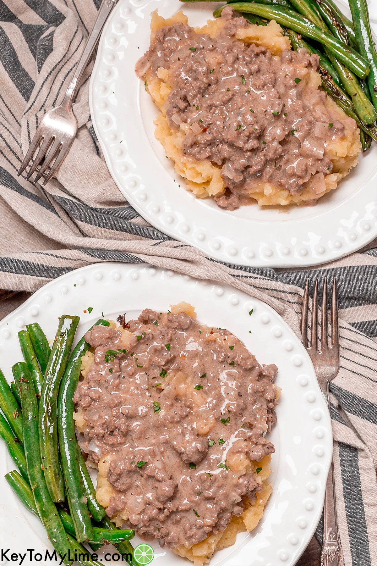 An overhead image of two dinner plates filled with mashed potatoes and gravy on top.