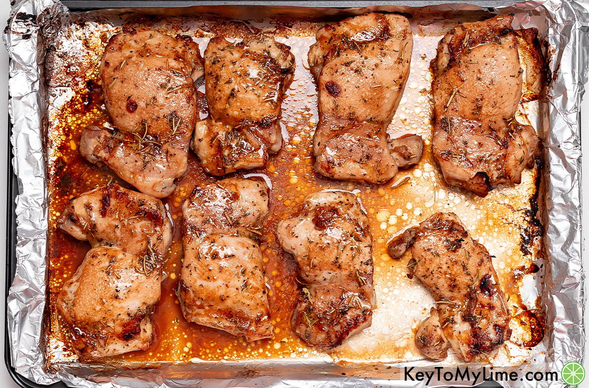 Removing the chicken thighs from the oven once they have a golden texture.