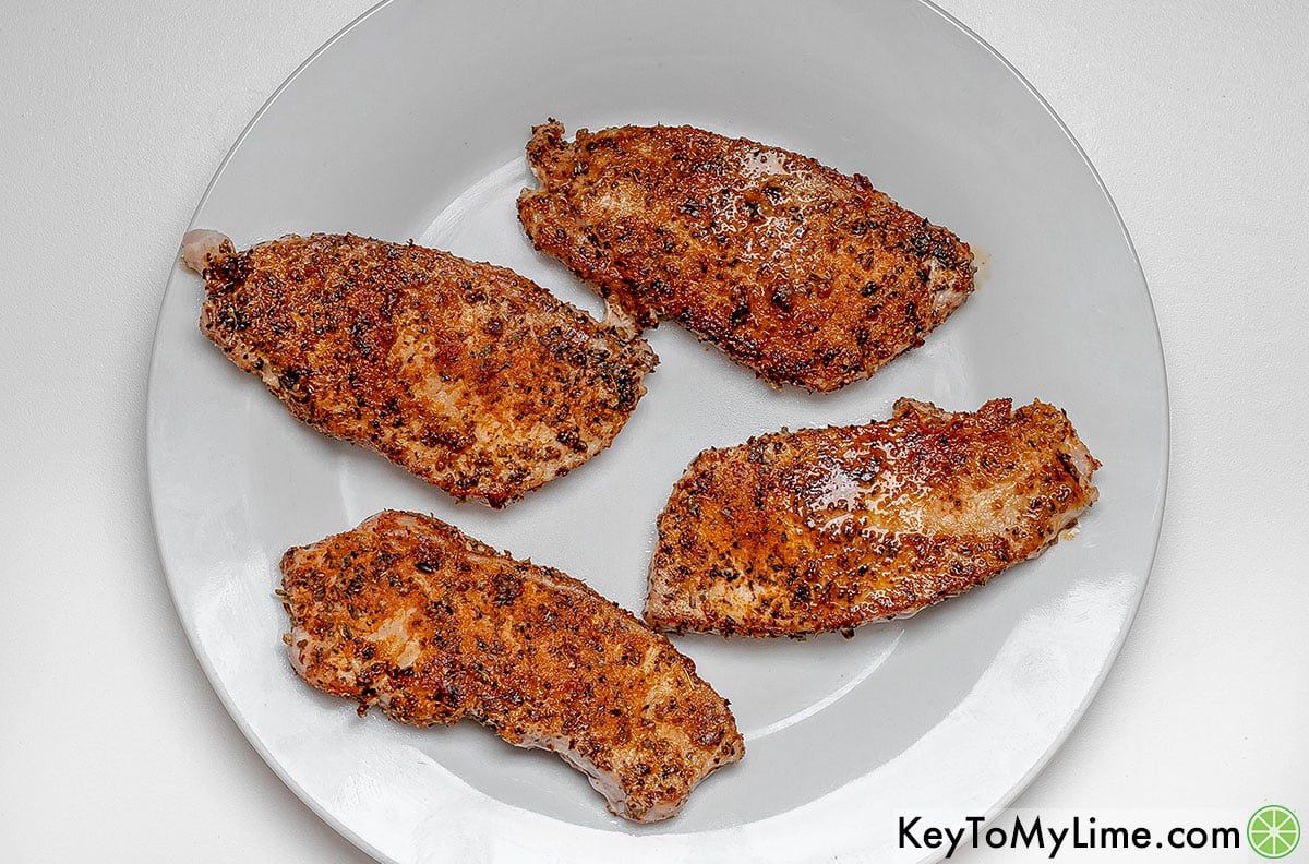Removing pork chops from the skillet, and resting on a plate.