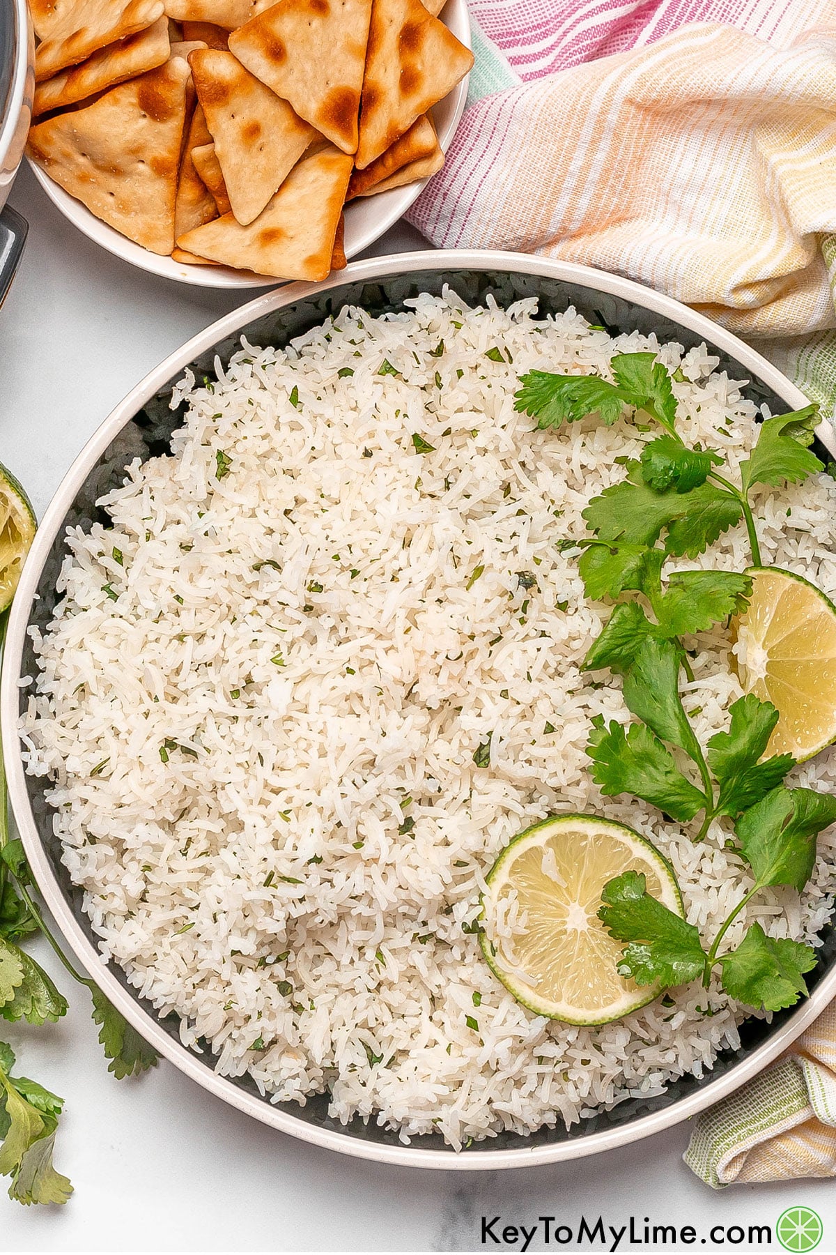 An overhead image of rice mixed with cilantro and lime wedges to the side.