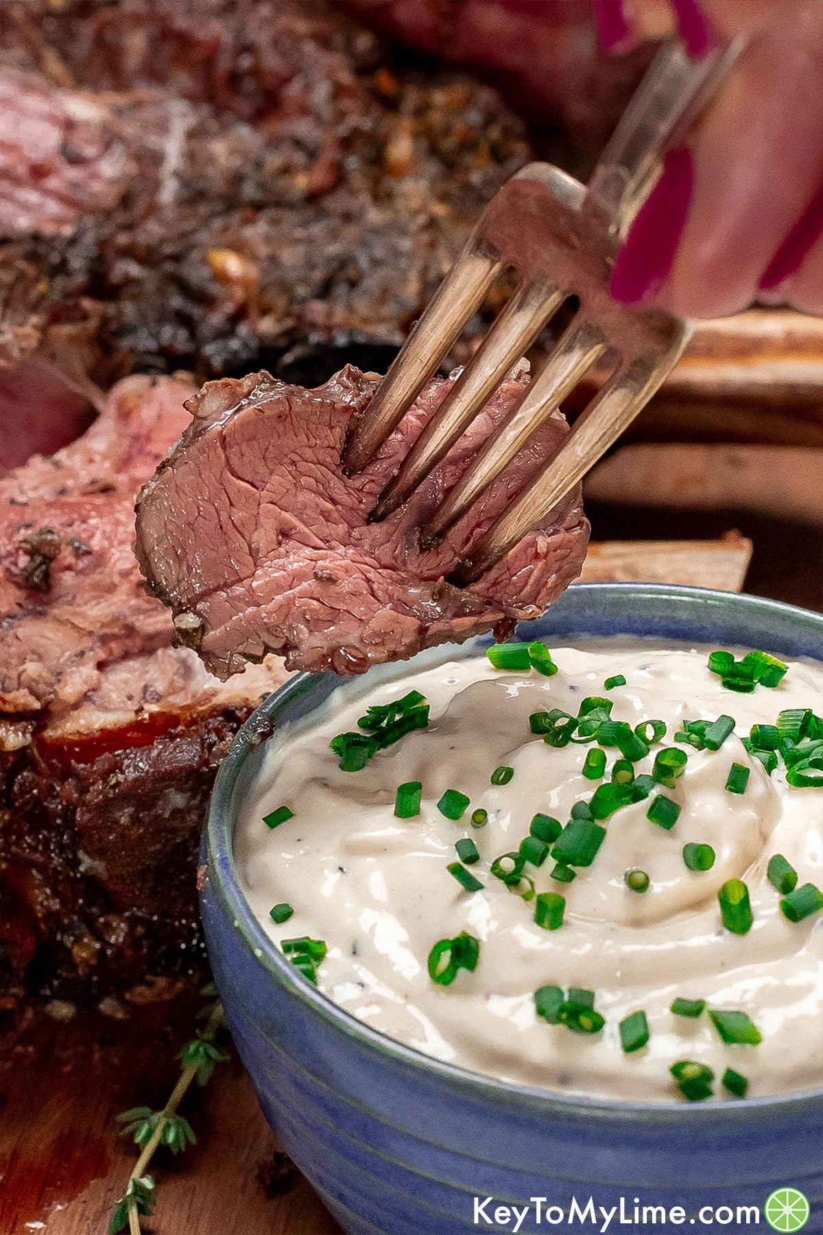A close up image of a slice of ribeye on a fork.
