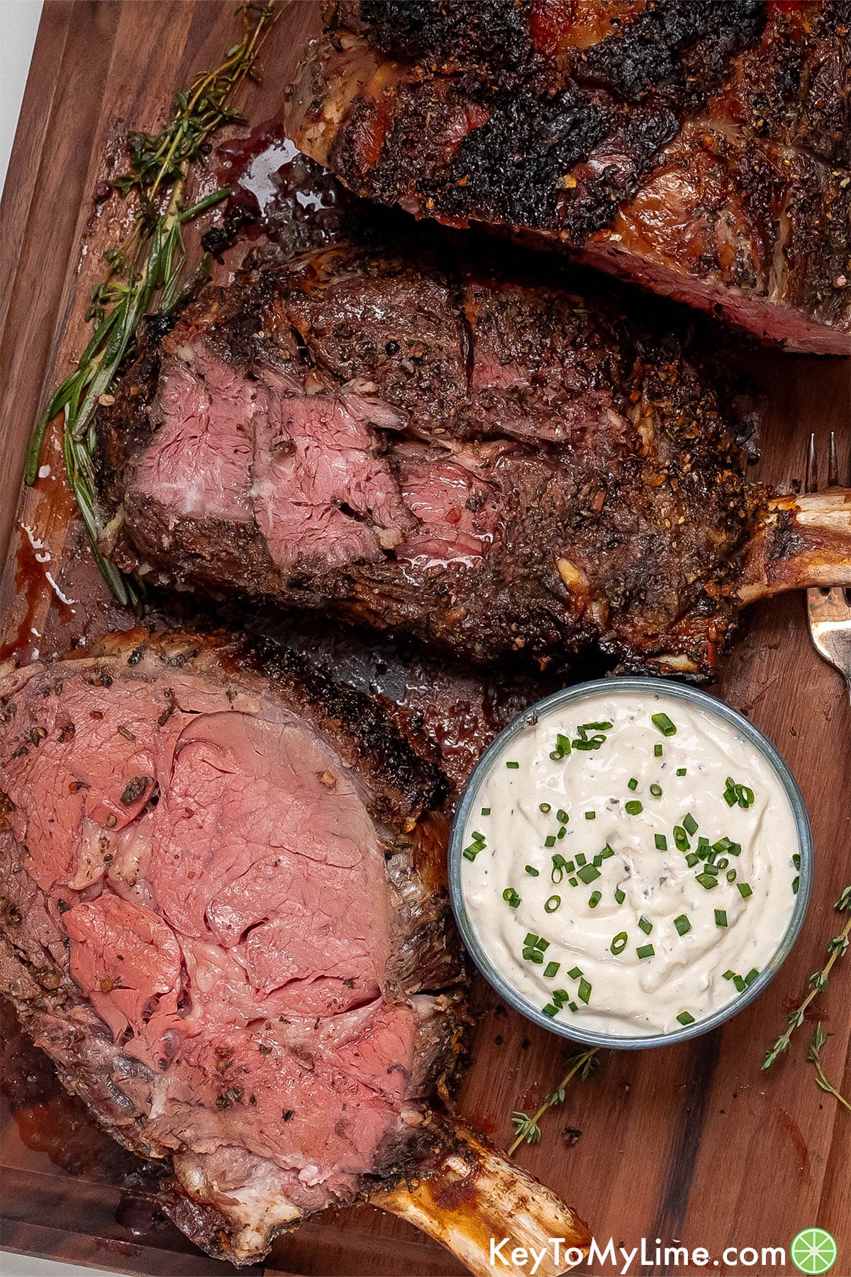A sliced ribeye with homemade horseradish sauce on a cutting board.